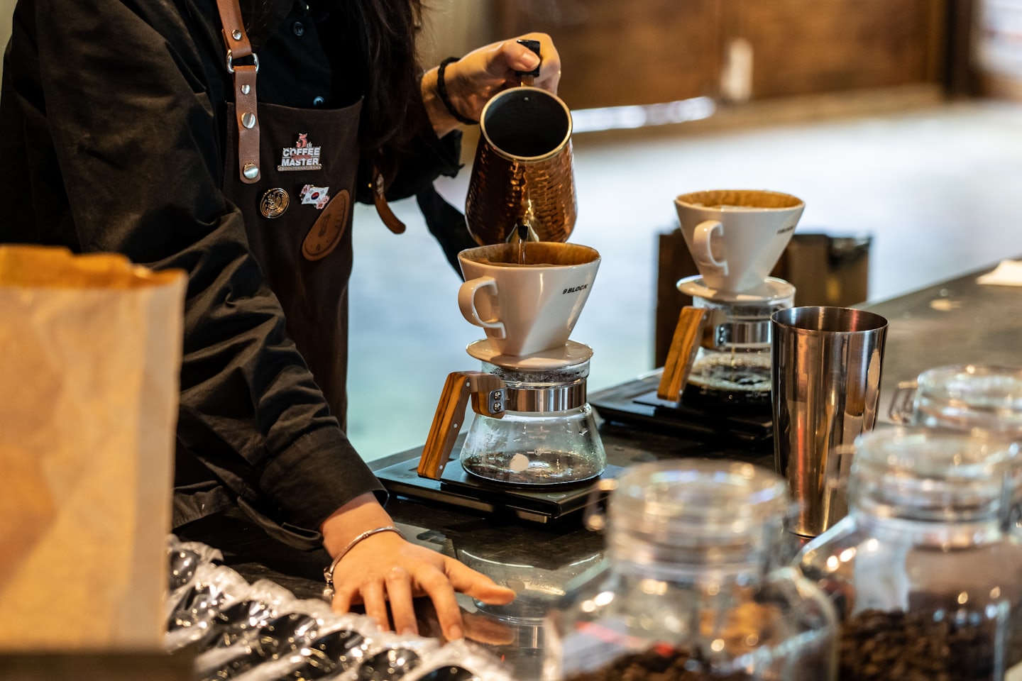 Barista zet koffie met een pourover-filter achter de bar
