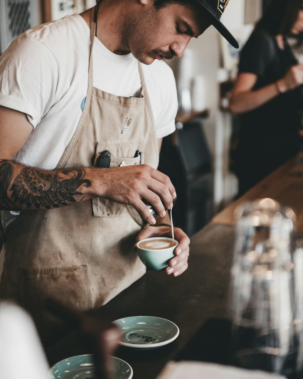 Barista giet melk voor latte art in een kopje koffie