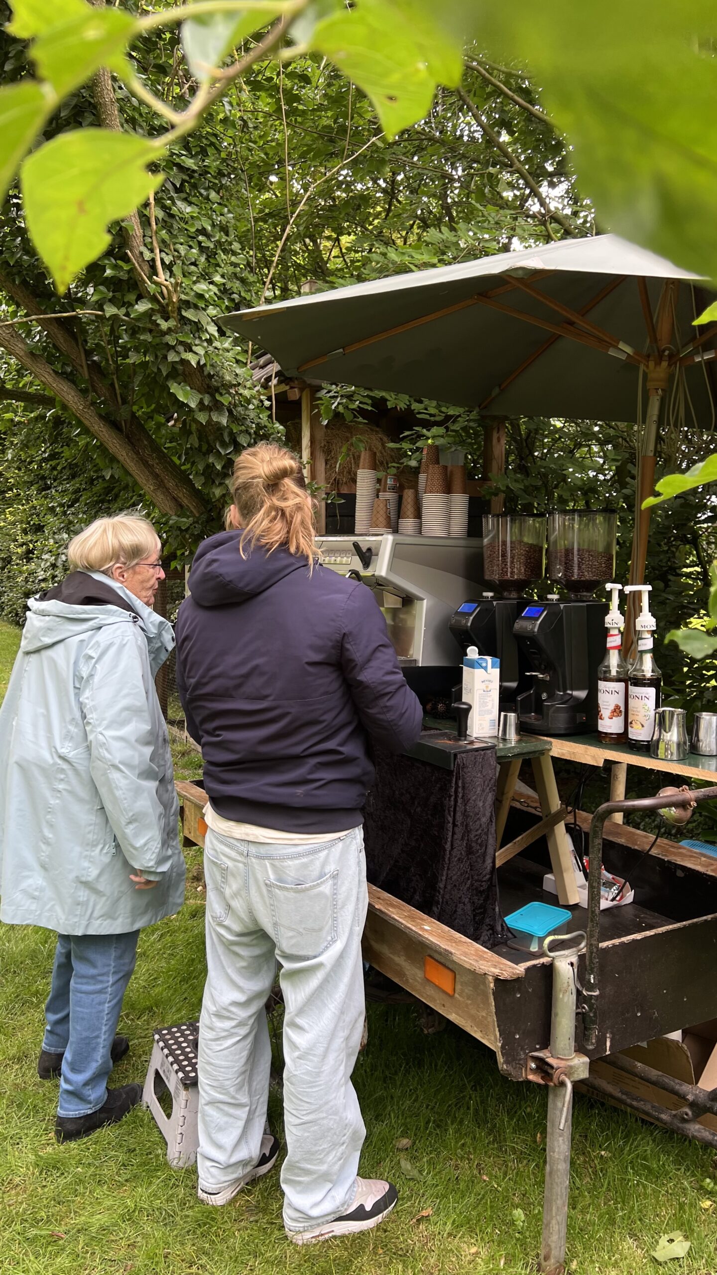Barista van Absoluukt zet koffie voor een gast op een mobiele koffiekar buiten tijdens een evenement